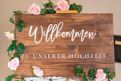 pexels-photo-14365407-14365407 Wooden welcome sign adorned with pink roses for a wedding celebration.